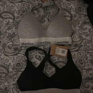 Två Calvin Klein bh-ar  - Säljer två Calvin Klein sporttoppar i grått och svart.  Helt nya säljer då dem är för små för mig 