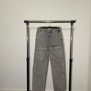 Grå cargobyxor jeans från Zara - Snygga grå cargobyxor från Zara med flera praktiska fickor och en avslappnad passform. Perfekta för en casual look med en touch av stil. Storlek eu 38