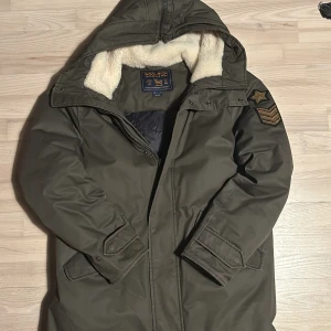 Olivgrön/militärgrön jacka från Woolrich - Snygg olivgrön parkajacka från Woolrich med mysigt foder och huva. Jackan har en dragkedja och flera praktiska fickor. Perfekt för kyliga dagar. Denna jacka kostade ny närmare 8000-9000kr. Jag säljer den nu endast för 4000kr. Jackan är endast använd denna vinter och har noll defekter. Först till kvarn!