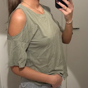 Olivgrön topp med öppna axlar - Snygg olivgrön topp med öppna axlar och korta ärmar. Från Hunky Dory. Skrynklig pga att den legat nerpackad. Knappt använd och är i super skick. Ord.pris runt 1300kr