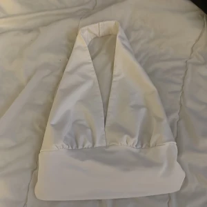 Vit halterneck topp - Snygg vit halterneck topp med bred kant nedtill. Perfekt för sommarens varma dagar. Enkel och stilren design som passar till många olika outfits.