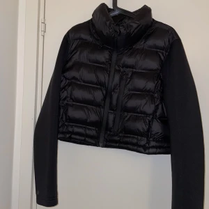 Svart pufferjacka med dragkedja Zara - Snygg svart pufferjacka med dragkedja och långa ärmar. Jackan har en quiltad design och är perfekt för kyligare dagar. Den har en hög krage för extra värme och stil.