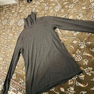 Grå polotröja från Divided - Säljer en stilren grå polotröja från Divided. Tröjan har långa ärmar och en klassisk polokrage, perfekt för kyligare dagar. Tillverkad i ett mjukt och bekvämt material.