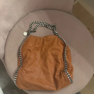 Stella McCartney väska - Säljer denna fina Stella McCartney väska som är i fint skick. Mellan storleken. Den är lite brun/orange rostig i färgen. Super fin och unik. Hör av er vid frågor!