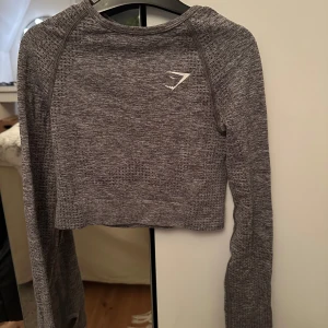 Grå croppad träningstopp Gymshark - Säljer denna grå croppade träningstopp från Gymshark. I fint skick, jätte bekväm, strl XS, 100kr+frakt! 🤍
