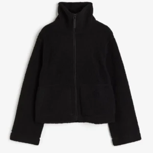 Svart teddyjacka med dragkedja - Mysig svart teddyjacka med hög krage och dragkedja framtill. Perfekt för kyliga dagar med sin mjuka och varma känsla. Jackan har långa ärmar och en enkel design som passar till det mesta.💕