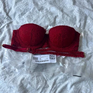 Röd spets-bh från H&M - Säljer en supersnygg röd spets-bh från H&M. Den är vadderad och har avtagbara axelband som medföljes. Helt ny med prislappen kvar, säljes pga av att den var i fel storlek.