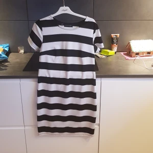 Randig klänning från Bodyflirt - Snygg svartvit randig klänning från Bodyflirt. Den har korta ärmar och en klassisk rund halsringning. Perfekt för en stilren look.