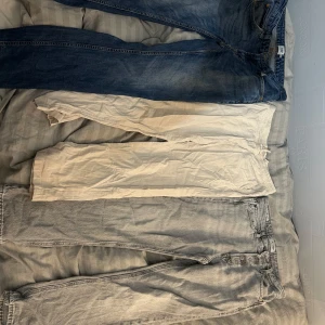 Två par byxor från Jack & Jones och ett par ifrån Lindex - Säljer tre par byxor från Jack & Jones. Ett par blå jeans med normal passform, ett par grå jeans med relaxed fit och ett par beige linnebyxor med snörning i midjan. Perfekta för olika tillfällen och stilar. Jeansen storlek 32/33 och passar 170/175. Medans linnebyxora passar 164