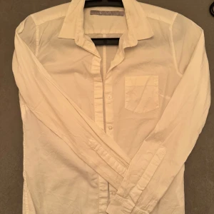 Vit damskjorta från Tiger - Klassisk vit skjorta i strech från Tiger med långärmad design och en bröstficka. Perfekt för en stilren look. Skjortan har knappar framtill och en traditionell krage.