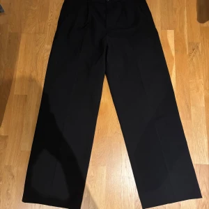 Svarta kostymbyxor från Weekday - Snygga svarta kostymbyxor från Weekday med en klassisk design. Byxorna har en rak passform och är midwaist. Perfekta för en stilren look. Bra skick, defekter på innersidan med en knapp som lostnat.