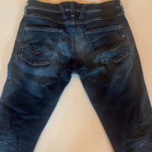 Mörkblå replay jeans med slitningar - Snygga mörkblå jeans med diskreta slitningar och klassisk femficksdesign. Jeansen har en slim passform och är perfekta för en stilren look. De har en dragkedja och knapp framtill.