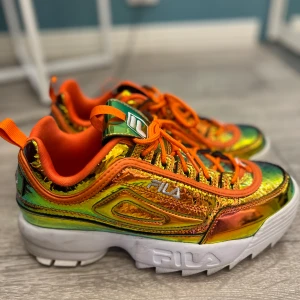 FILA skor (ovanliga, finns inte mer att få tag i) - Säljer ett par unika och färgglada Fila sneakers i orange och grönt med glansig finish. Skorna är väldigt sköna! Perfekta för alla! De är i ett väldigt bra skick, använda bara en gång till och från skolan! Säljer de eftersom de är köpta i fel storlek och passar inte mig! 
