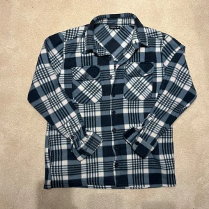 Fleece Overshirt  - Snygg blå och vit rutig overshirt. Perfekt för lager-på-lager-stil med knappar framtill och två bröstfickor. Tillverkad i mjukt material för en bekväm känsla. Vid minsta fråga eller fundering hör av er🤝