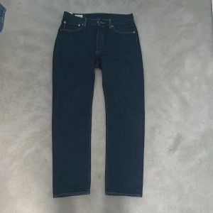  Levi's 501 - Snygga mörkblå Levi's jeans (501) med klassisk femficksdesign och guldfärgade nitar. De har en rak passform och är tillverkade i slitstarkt denim. Perfekta för en stilren look. Ny skick!