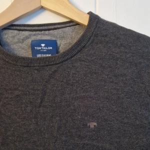 Grå tröja från Tom Tailor - Säljer en stilren grå tröja från Tom Tailor. Tröjan har en rund halsringning och långa ärmar.