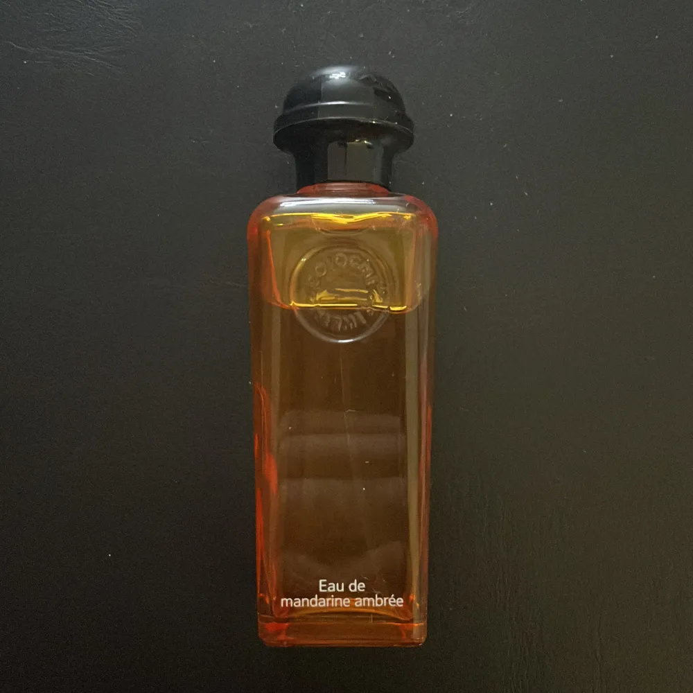 Elegant parfymflaska med en varm orange ton och svart lock. Doften är fräsch och citrusaktig med inslag av mandarin och bärnsten. Perfekt för den som älskar en lätt och uppfriskande doft. 100 ml . Perfume.