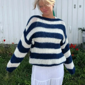 Randig stickad tröja i blått och vitt - Mysig stickad tröja med breda ränder i blått och vitt. Tröjan har en avslappnad passform och långa ärmar, perfekt för kyligare dagar. Den är både stilren och bekväm, vilket gör den till ett måste i garderoben. Storlek S