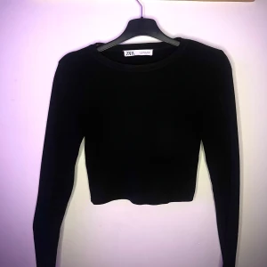 Svart croppad tröja från Zara - Säljer en stilren svart croppad tröja från Zara. Tröjan har långa ärmar och en enkel design som passar perfekt till olika outfits. Tight basic tröja som passar till allt.