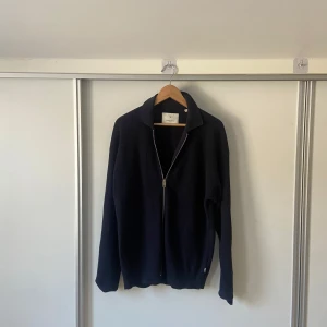 Mörkblå ziptröja  - Säljer en stilren mörkblå zip tröja från Jack and Jones premium. Tröjan har en dragkedja framtill och är ribbad för en snygg textur. Tröjan är i princip helt oanvänd då jag använt den 1-2 gånger. Köpte den för 800 kr på Jack and Jones och den är nyskick! Kan gå ned i pris vid snabb affär! Inga returer!