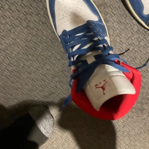 Nike Air Jordans i blått, vitt och rött - Snygga Nike Air Jordans i en fräsch färgkombination av blått, vitt och rött. Skorna har klassisk snörning och en ikonisk logga på sidan. Perfekta för dig som vill ha en stilren och sportig look. Priset är ej hugget i sten om ni har några frågor vänligen kontakta mig☺️