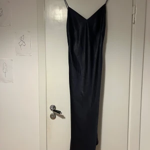 Marinblå långklänning från Filippa K - Elegant marinblå långklänning i satin från Filippa K med smala axelband och v-ringning. Inköpt för ca 2000 kr men har en liten repa (se bild) så säljs billigt! 