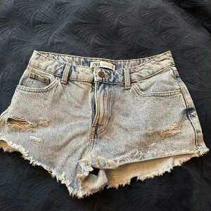 Blå jeansshorts från Zara - Snygga blå jeansshorts från Zara med slitna detaljer och fransig kant. Skit snygga