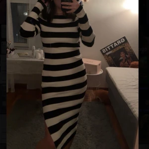 Randig långklänning - Snygg randig långklänning i svart och vit med långa ärmar. Klänningen har en stretchig passform och en liten slits på sidan. Perfekt för en stilren look. I storlek M från stradvarius. Prislapp på. 