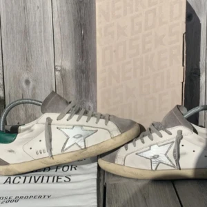 Golden Goose sneakers  - Snygga Golden Goose sneakers i vitt och grått med den ikoniska stjärndetaljen. Perfekta för en avslappnad stil. Box är med !  uppslitna på hälarna/hål Sicka för att få mer bilder  