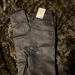 Svarta byxor från Lager 157 - Snygga svarta byxor från Lager 157 i storlek XS. Byxorna har en klassisk femficksdesign och är perfekta för en stilren look. De är tillverkade i ett material som ger en lätt glansig finish.