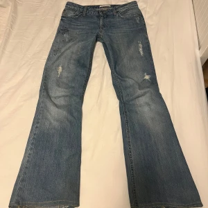 Blå bootcut jeans - Säljer ett par blå bootcut lågmidjade jeans från odd molly med slitna detaljer och broderade mönster. Passar mig som är 160 cm Midjemått: 36 Innebenslängd: 68 cm