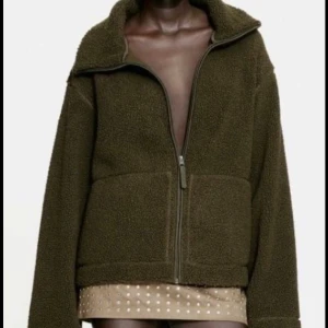 Olivgrön teddyjacka med dragkedja - Mysig olivgrön teddyjacka med dragkedja framtill. Jackan har en hög krage och stora fickor, perfekt för kyliga dagar. Den är långärmad.  Fråga om bilder hur den ser ut på💕