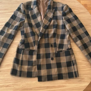 Rutig dubbelknäppt kavaj - Brun och svart rutig dubbelknäppt kavaj. Väldigt skönt material och fin passform