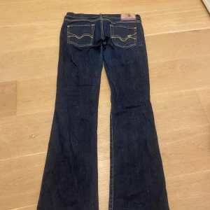 Mörkblå bootcut jeans - Snygga mörkblå bootcut jeans, as gullig detalj på fickorna. lite sliten längst ner på ena benet annars inget märkvärdigt  midja 40 