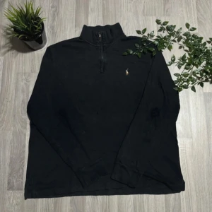 Svart tröja med dragkedja från Ralph Lauren - Säljer en stilren svart tröja från Ralph Lauren med halv dragkedja och broderad logga på bröstet. Tröjan är tillverkad i 100% bomull och har långa ärmar. Perfekt för en avslappnad look. Är utsliten på armbågarna och lite på fram sidan. Alla beställningar skickas inom 24 timmar!🌍📦