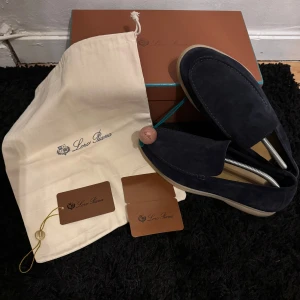 Mörkblå loafers från Loro Piana - Snygga mörkblå loafers från Loro Piana i mocka. Skorna har en stilren design med en ljus sula som ger en fin kontrast. Skorna är i väldigt bra skick men har små tecken på användning vilket man ser på bilderna. Skorna är i strl 44 men skulle säga att dem även passar 43. Priset är prutbart till en rimlig nivå.