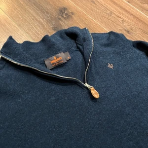 Mörkblå tröja med dragkedja från Morris - Snygg mörkblå tröja från Morris med en stilren dragkedja och broderad logga på bröstet. Perfekt för en avslappnad men ändå elegant look. Tröjan har långa ärmar och en bekväm passform. Nypris 1800kr! Det står storlek M men passar som S