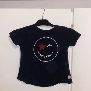 Svart t-shirt med tryck - Cool svart t-shirt från 157 med ett tryck av en röd stjärna och texten 'Hello World'. Perfekt för en avslappnad stil. Kortärmad och tillverkad i ett bekvämt material.