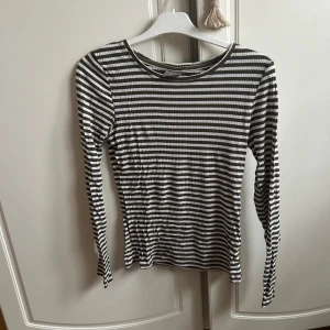 Randig långärmad topp från Vero Moda - Säljer en randig topp från Vero Moda i grönt och vitt. Den har en tight passform och är långärmad, perfekt för både vår och höst. Materialet är ribbat vilket ger en skön och stretchig känsla. Passar utmärkt till jeans eller kjol för en stilren look.