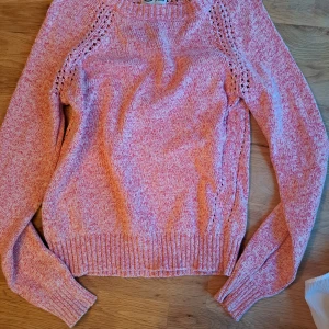 Rosa stickad tröja - Säljer en mysig rosa stickad tröja med fina detaljer längs ärmarna. Tröjan har långa ärmar och ribbstickade muddar vid ärmslut och nederkant. Perfekt för kyliga dagar!