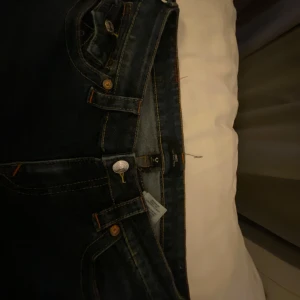 Mörkblå jeans från True Religion - Snygga mörkblå jeans från True Religion med låg midja och flare-stil. De har dekorativa sömmar på bakfickorna,dock är det lite defetioner där nere på baksidan som man ser på bilden.pris kan diskuteras 