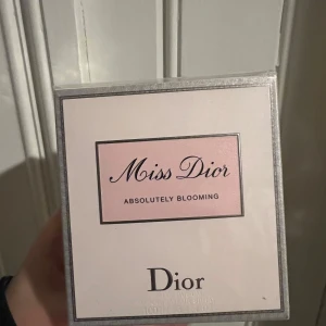 Miss Dior Absolutely Blooming Parfym - Miss Dior Absolutely Blooming är en elegant parfym från Dior. Flaskan är stilren med en rosa vätska och en silverfärgad rosett vid spraymunstycket. Perfekt för den som älskar blommiga och fruktiga dofter.