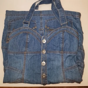 Blå jeansklänning - Säljer en unik blå jeansklänning med knappar framtill. Perfekt för sommaren. Passar S även om det är 34. Garderobsrensning så kika gärna på övriga auktioner. 