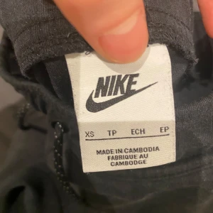 Svarta mjukisbyxor från Nike - Säljer ett par svarta mjukisbyxor från Nike i storlek XS. Byxorna har en elastisk midja med snörning och en  Nike-logga på benet. Perfekta för en avslappnad stil och den är varm.
