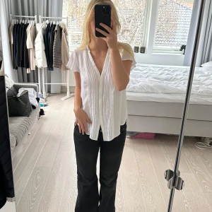 Vit blus med v-ringning - Säljer en stilren vit blus med v-ringning och korta ärmar. Blusen har en lös passform och är perfekt för en avslappnad look. Den är tillverkad i ett lätt och luftigt material som ger en skön känsla. Storlek 42 alltså XL. Passar XS-L skulle jag säga