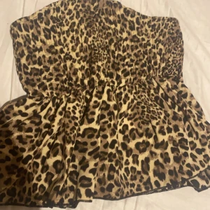 Leopardmönstrad tubtopp - Snygg leopardmönstrad tubtopp med smockdetaljer som ger en bekväm passform. Perfekt för att lägga till en djärv touch till din outfit. Aldrig använd