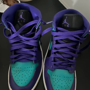 Nike Air Jordans i lila och turkos - Snygga Nike Air Jordans i en cool färgkombination av lila och turkos. Skorna har snörning och en klassisk design med perforerade detaljer på tån. Perfekta för dig som vill sticka ut med stil.