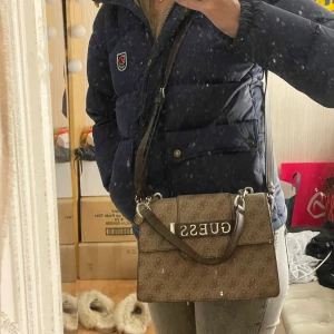 Brun handväska från GUESS - Jättefin väska från GUESS med tre fack som gör att den rymmer mycket men samtidigt är den diskret. Original påsen ingår. Knappt använd👜                                                Inköpt för 1000kr