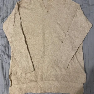 Beige tröja från ONLY - Säljer en beige tröja från ONLY med v-ringning. Tröjan har långa ärmar och ribbade muddar vid ärmslut och nederkant. Perfekt för en avslappnad stil.