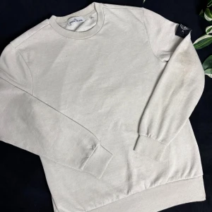 Ljusgrå Stone Island jumper  - En ljusgrå Stone Island jumper som har är i skick 8/10 anledningen som gör att det inte blir är en 10/10 är att det finns en fläck och 2 små hål, det finns även inte någon qr-kod den har tyvärr blivit avklippt. Måtten ~ 48x66cm